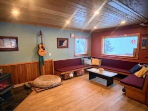 sitting room with bench style seating, guitar, wood stove, coffee table and healthy selection of games and books